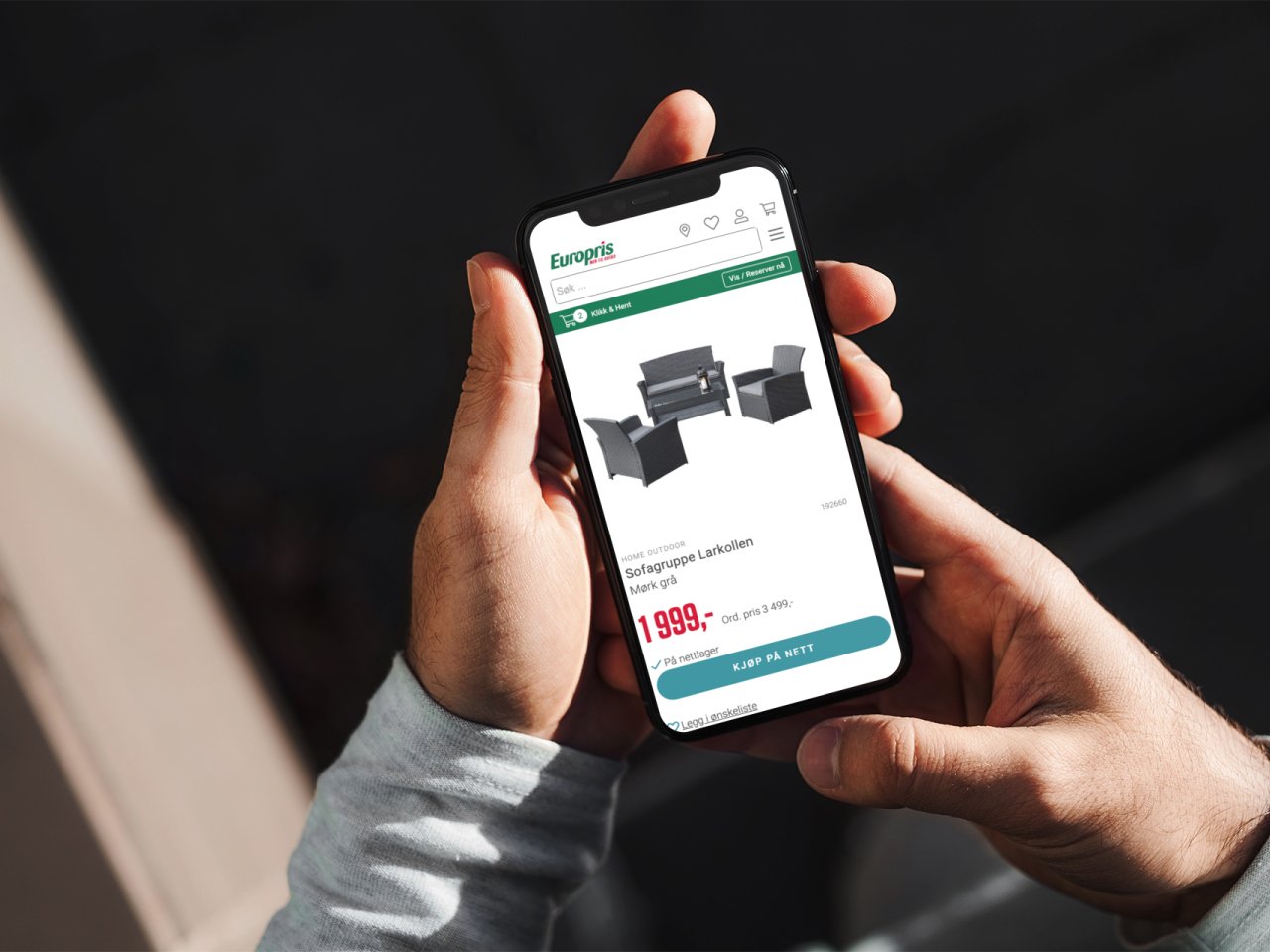 To hender som holder en telefon med en hagesittegruppe på europris.no på skjermen.