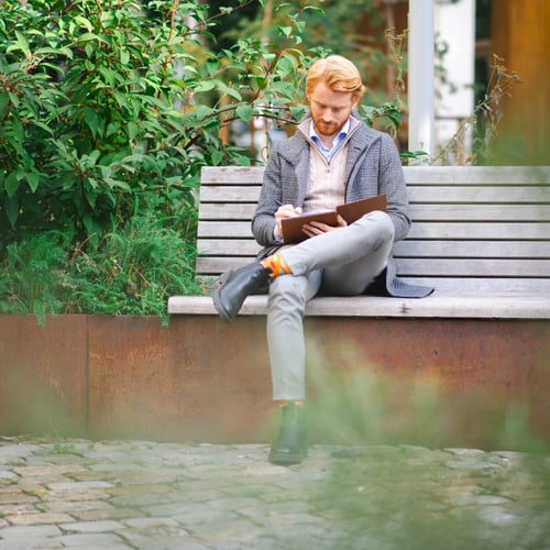 Mann sitter på en benk utendørs
