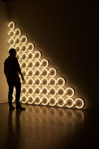 En mann står foran en vegg med lysende lamper